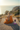 A woman with blonde hair in a bun sits cross-legged in a meditative pose on a stone terrace overlooking a coastal ocean at sunset. She is wearing a flowing orange garment, and a small stack of colorful candles rests beside her.