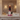 A decorative stacked candle holder or candle set displayed on a marble console table in an elegant interior. The centerpiece features a white sculpted face on a pink base, with stacked red, dark purple, and pink geometric elements above it.